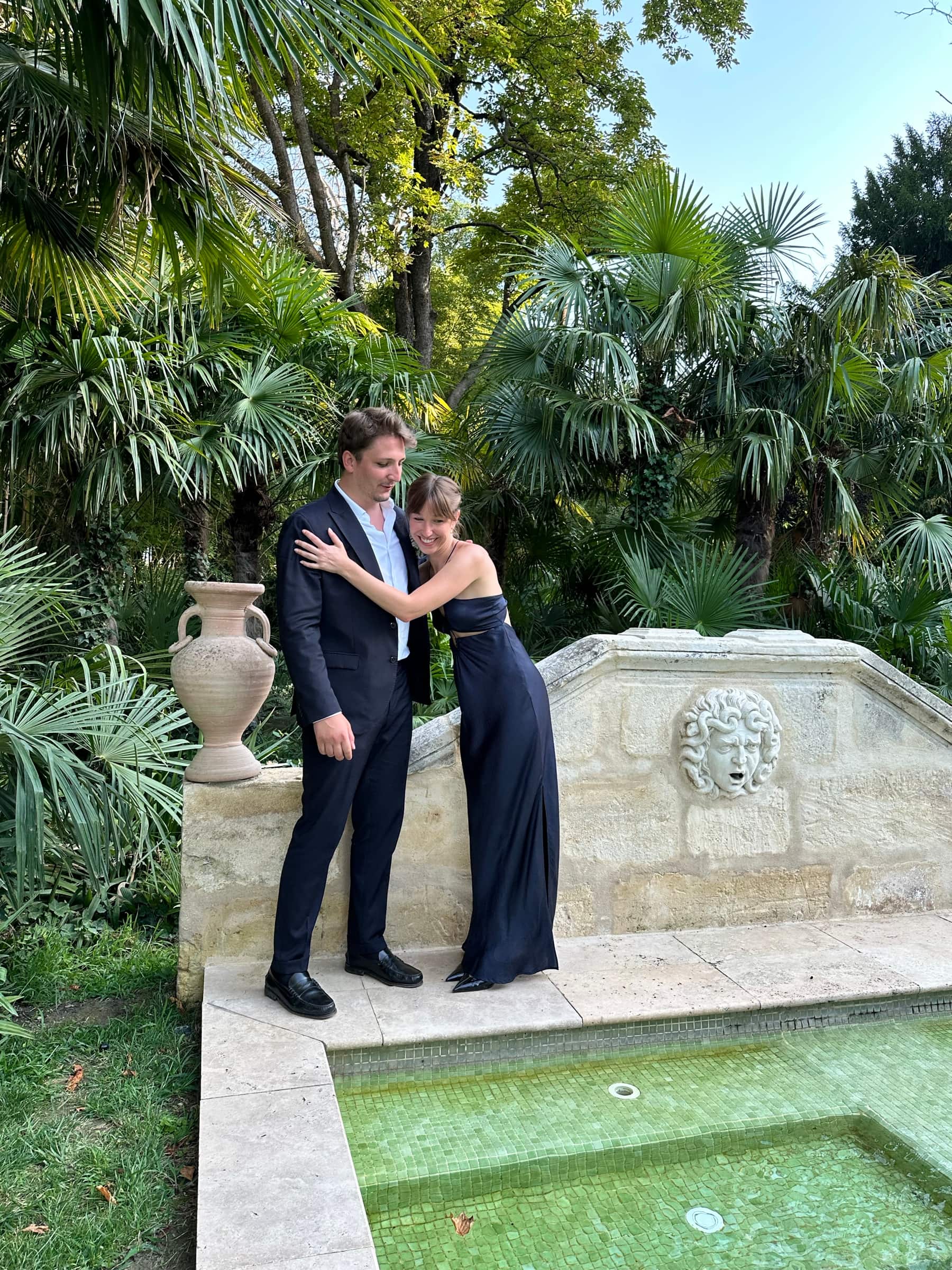 Romane et Lucas dans un jardin, près d'une fontaine en pierre